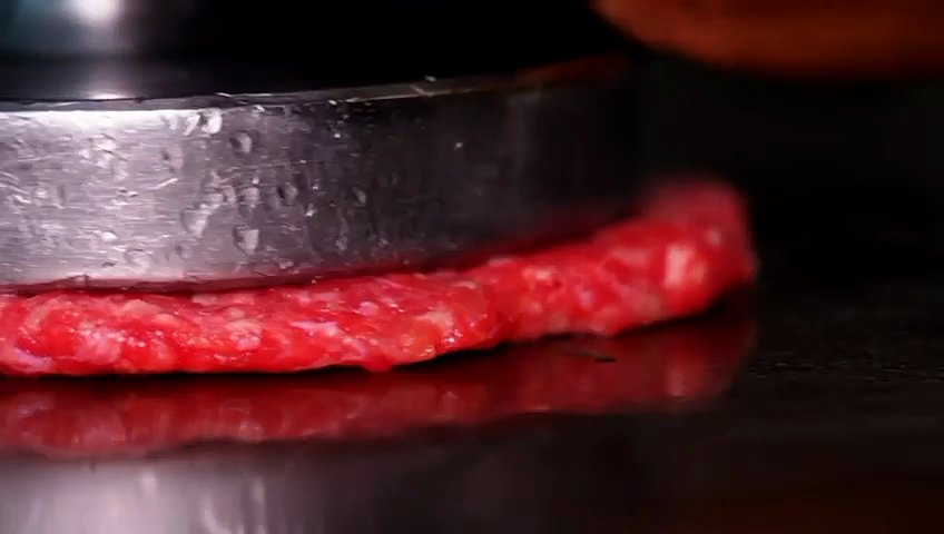 La presse écrase la boule de bœuf crue sur la plaque